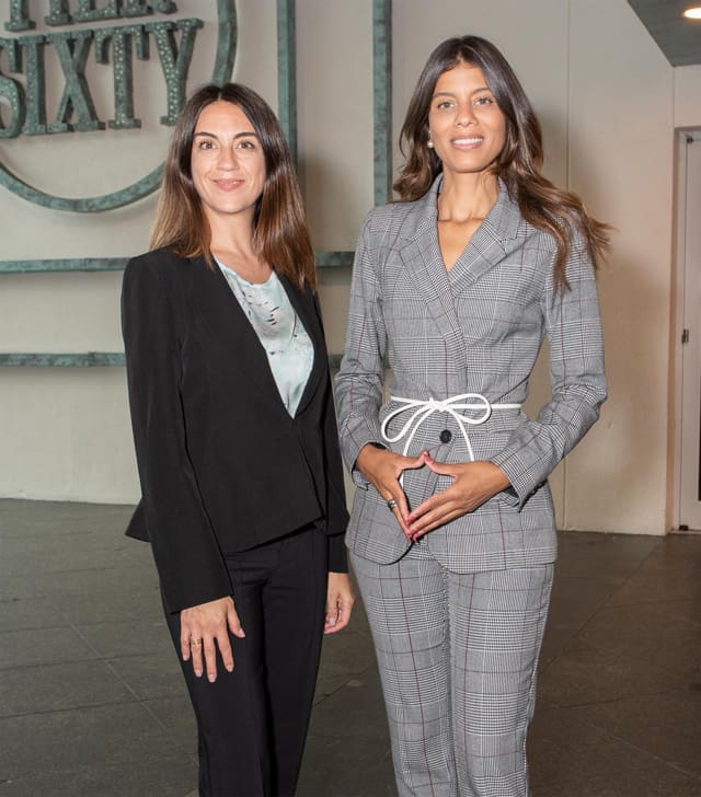 Two women in suits posing for a picture.