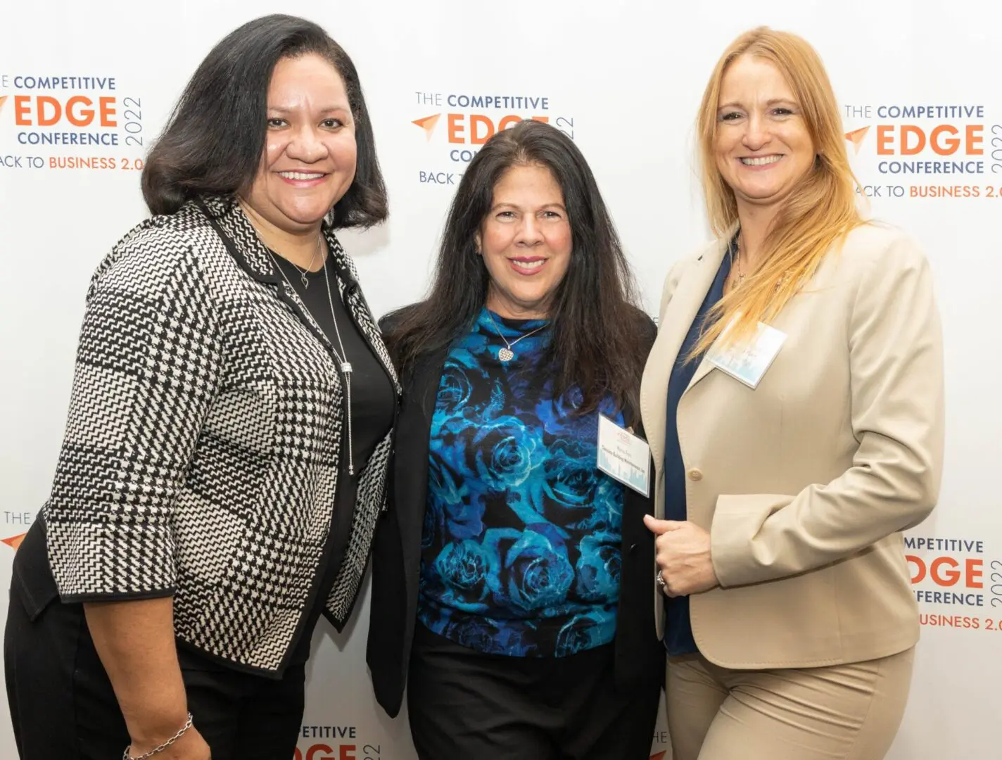 Three women standing next to each other in front of a wall.