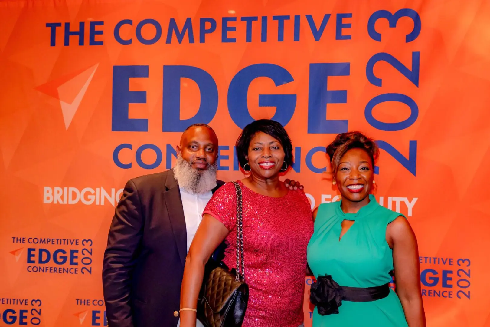 Three people standing in front of a sign that says " the competitive edge conference 2 0 1 3 ".