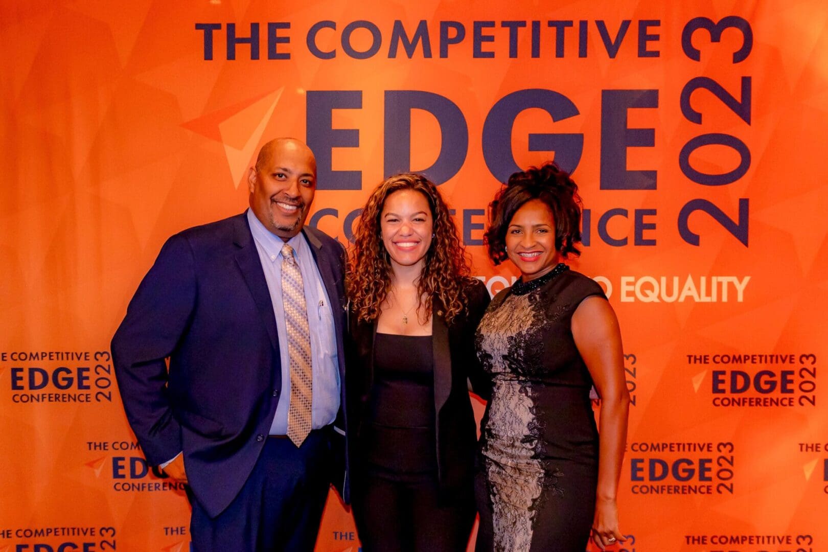 A group of people standing in front of an orange wall.