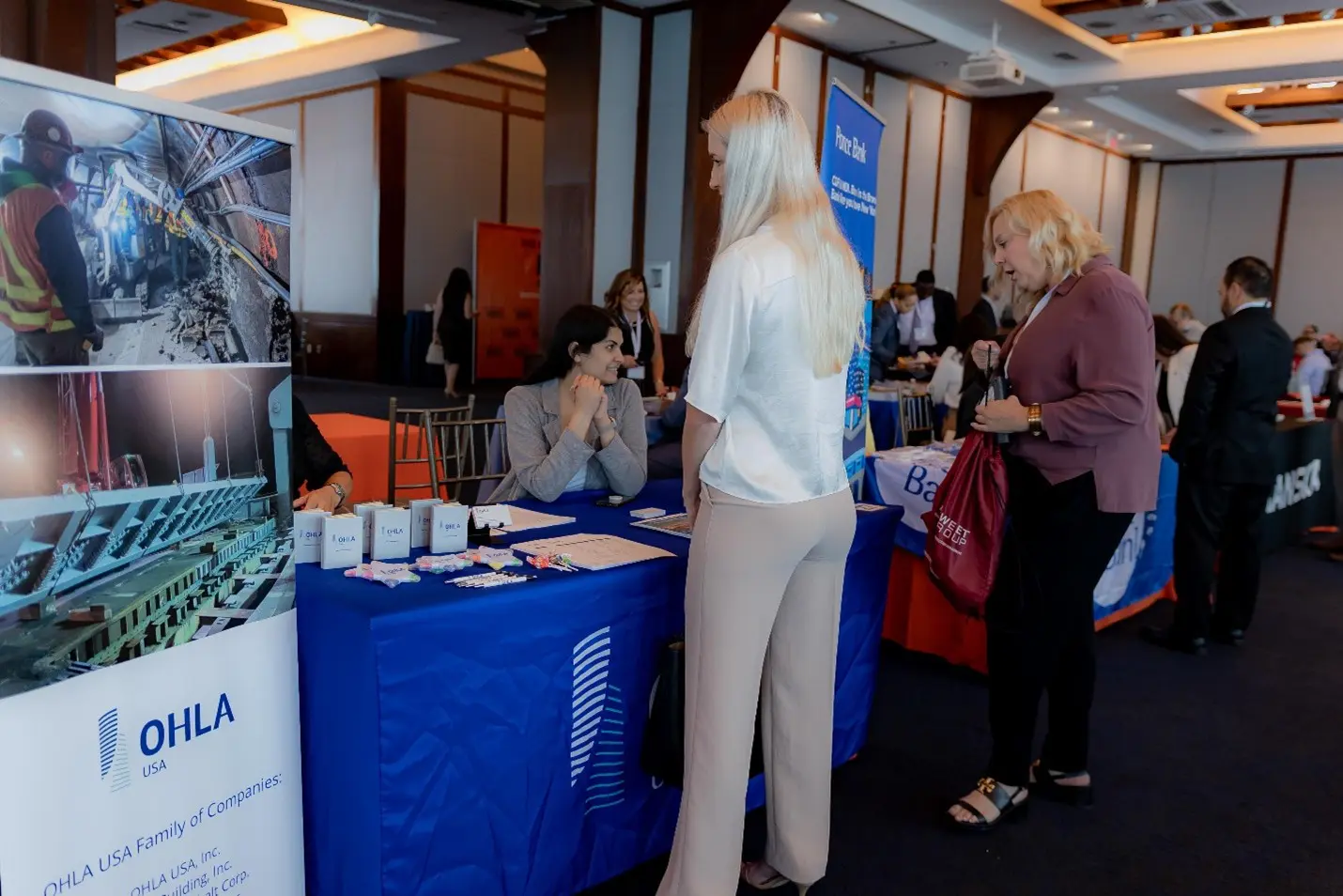 A woman standing in front of a table with other people.